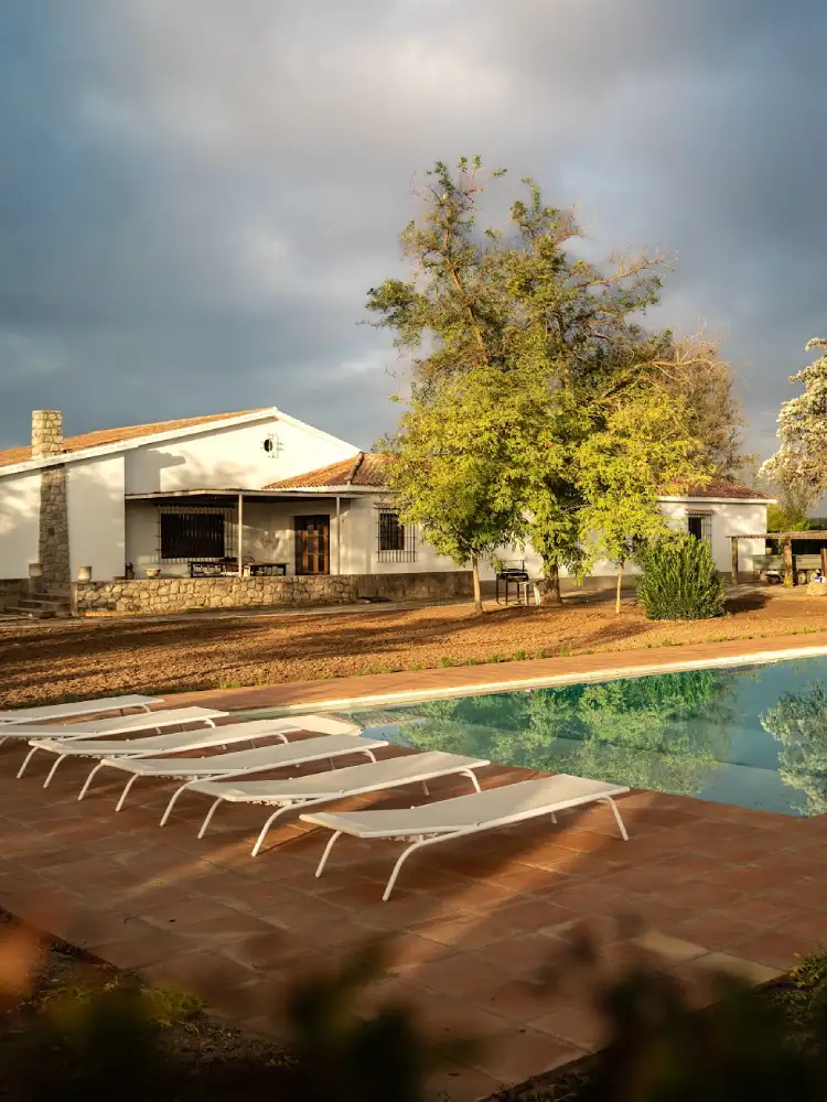 foto de la piscina de la casa rural, con unas hamacas y la casa de fondo